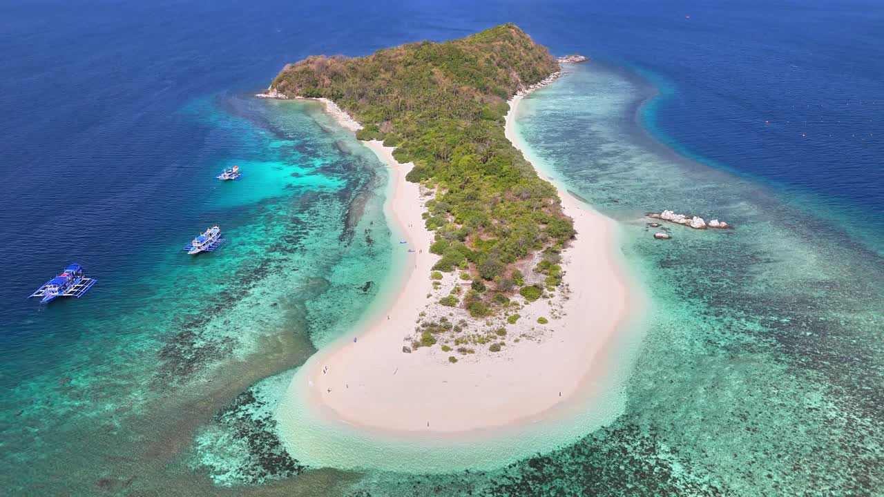 Aerial view of Manlihan Island in Linapacan, Philippines featuring white sand beaches, clear turquoise waters, coral reefs, and lush green foliage surrounded by traditional boats and shallow reefs