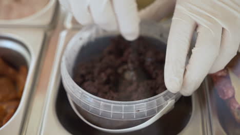 chef tomando tapenade de aceituna negra de un frasco de plástico, tiro cercano