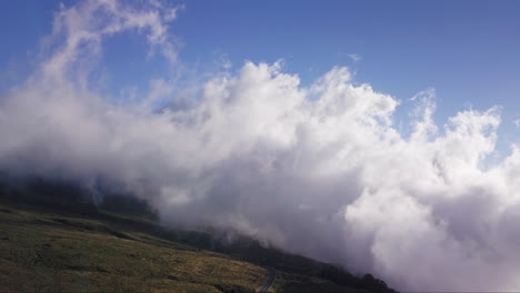 stratus clouds gather thick fluffy white forms rising from slopes of haleakala