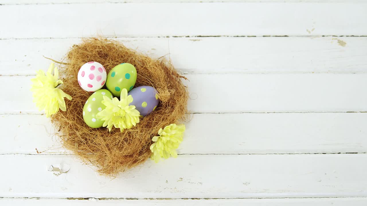 Painted Easter eggs in the nest on wooden surface