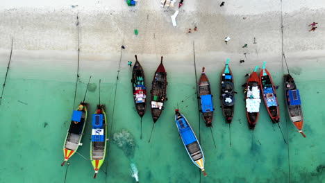 vista superior de una playa con barcos y hombres descargando carga