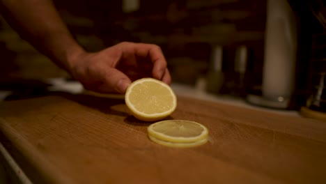 Slicing-fresh-lemon-with-serrated-knife-on-wooden-chopping-board,-STILL