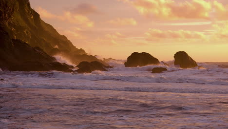 rough waves breaking against the rocks and cliffs during sunset