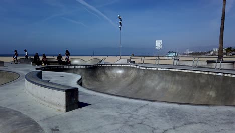 shot of an long hair guy skating in venice beach skate park bowl, los angeles