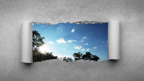 un video creativo de 4k de nubes que se mueven rápidamente en el cielo azul que son visibles a través de un agujero con bordes rasgados en viejo papel vintage retro grunge.