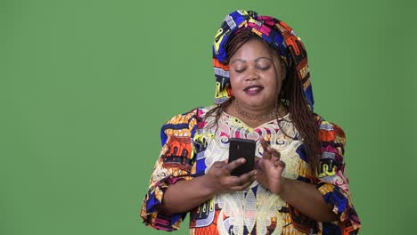 overweight beautiful african woman wearing traditional clothing against green background