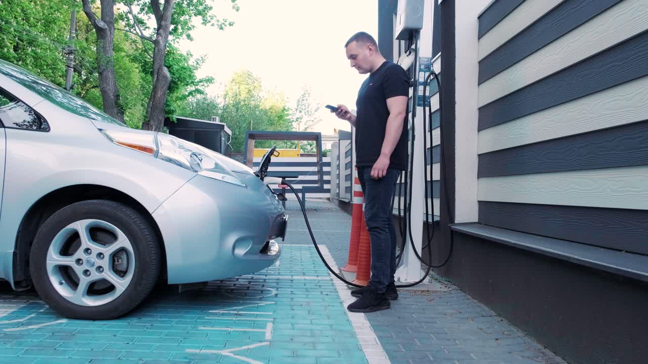 процесс заправки электромобиля. выстрел под люком, где заряжается электрический экомобиль. люк зарядки электрического автомобиля открывается автоматически. мужская рука вставляет эректильную машину
