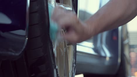 man washing rim of car.