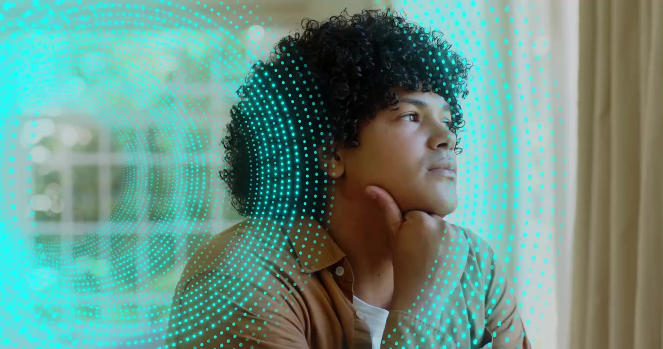 Mid adult man gazing by window and activating swirling turquoise particles forming holographic grid