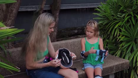 madre enseñando a su hija cómo usar el equipo de seguridad para patinar