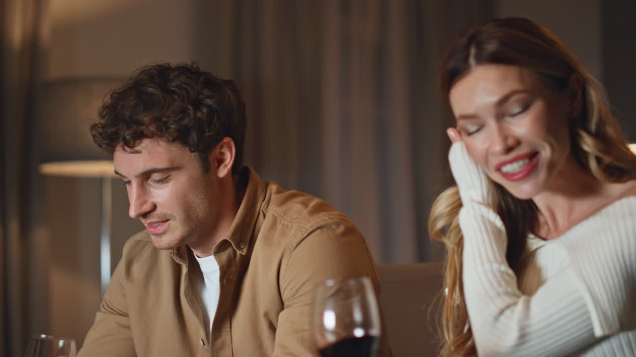 Romantic people enjoy wine spending evening together in dark apartment close up.