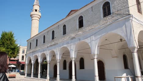 young tourist woman on cultural vacation. alacati pazaryeri mosque, dating from 1874, in alacati resort town town of izmir province in turkey