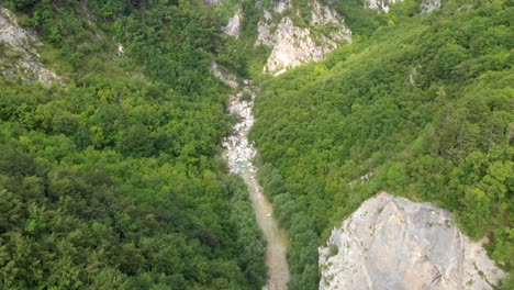 drone flying above wild river running through forest canyon in slovenia, tilt