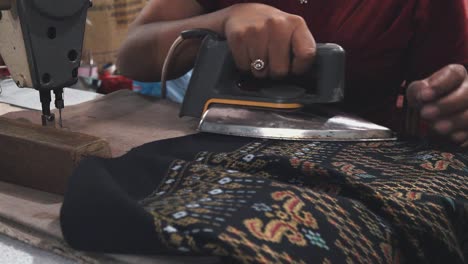 seamstress ironing a finished garment at the market