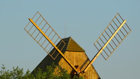 View-of-a-wooden-historic-mill-and-its-blades-standing-among-the-apple-trees