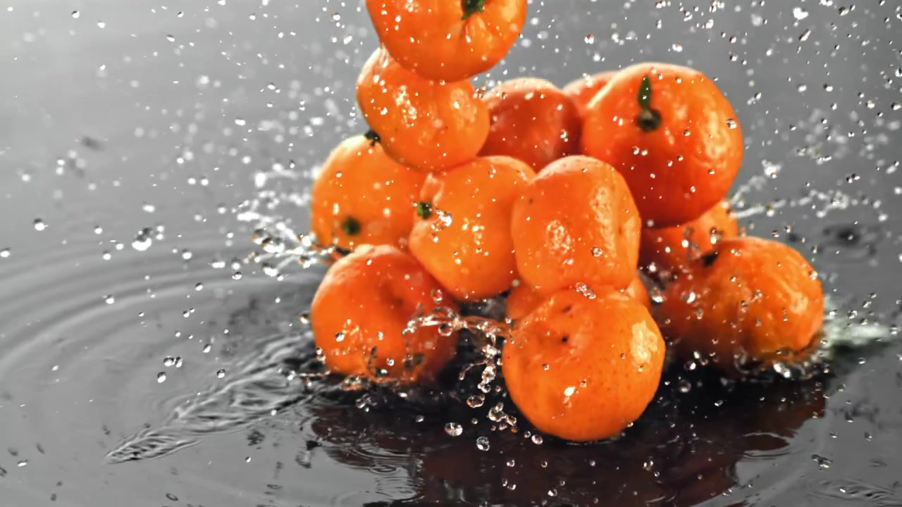 Friske mandariner falder ned i vand med plask i slowmotion