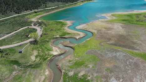 Aerial-View-of-Rifle-Gap-Dam,-Turquoise-Water-and-Green-Landscape,-State-Park-in-Colorado-USA,-Drone-Tilt-Up-Shot