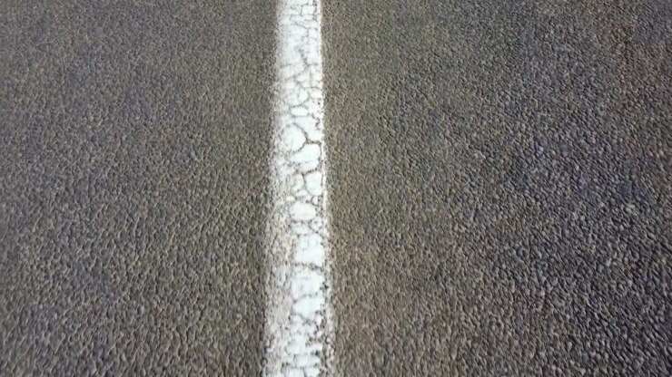 Center White Stripe On Asphalt, Cracked Paint And Rough Tarmac Texture Conveying Lonely Journey And Road Wear,