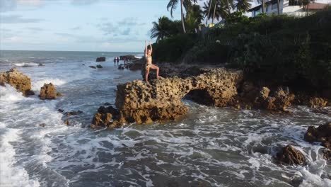 Mädchen,-Das-Auf-Einem-Felsen-Am-Rande-Des-Brasilianischen-Ozeans-Steht,-Schwenkt-Bis-Zum-Sonnenuntergang