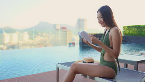 a young girl reading a book and relaxing by the swimming pool at a luxury hotel