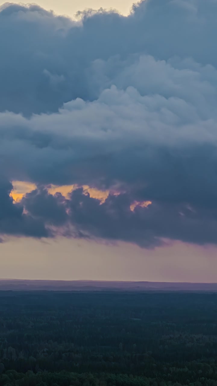 Dramatic clouds move over a forest landscape at sunset in a timelapse sequence