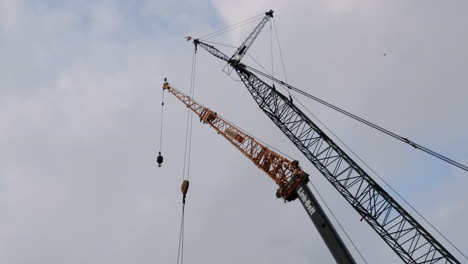 two large construction cranes against a cloudy sky