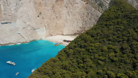 Vista-Aérea-De-Turistas-Y-Barcos-En-La-Playa-Navagio-Con-Naufragio-En-Un-Día-Soleado-De-Verano-En-Grecia