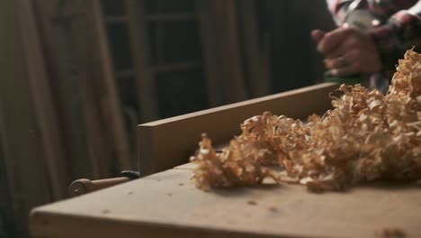 carpenter planing wood in moody workshop