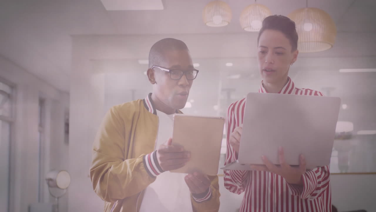 Collaborating on digital devices, two people in modern office using animation