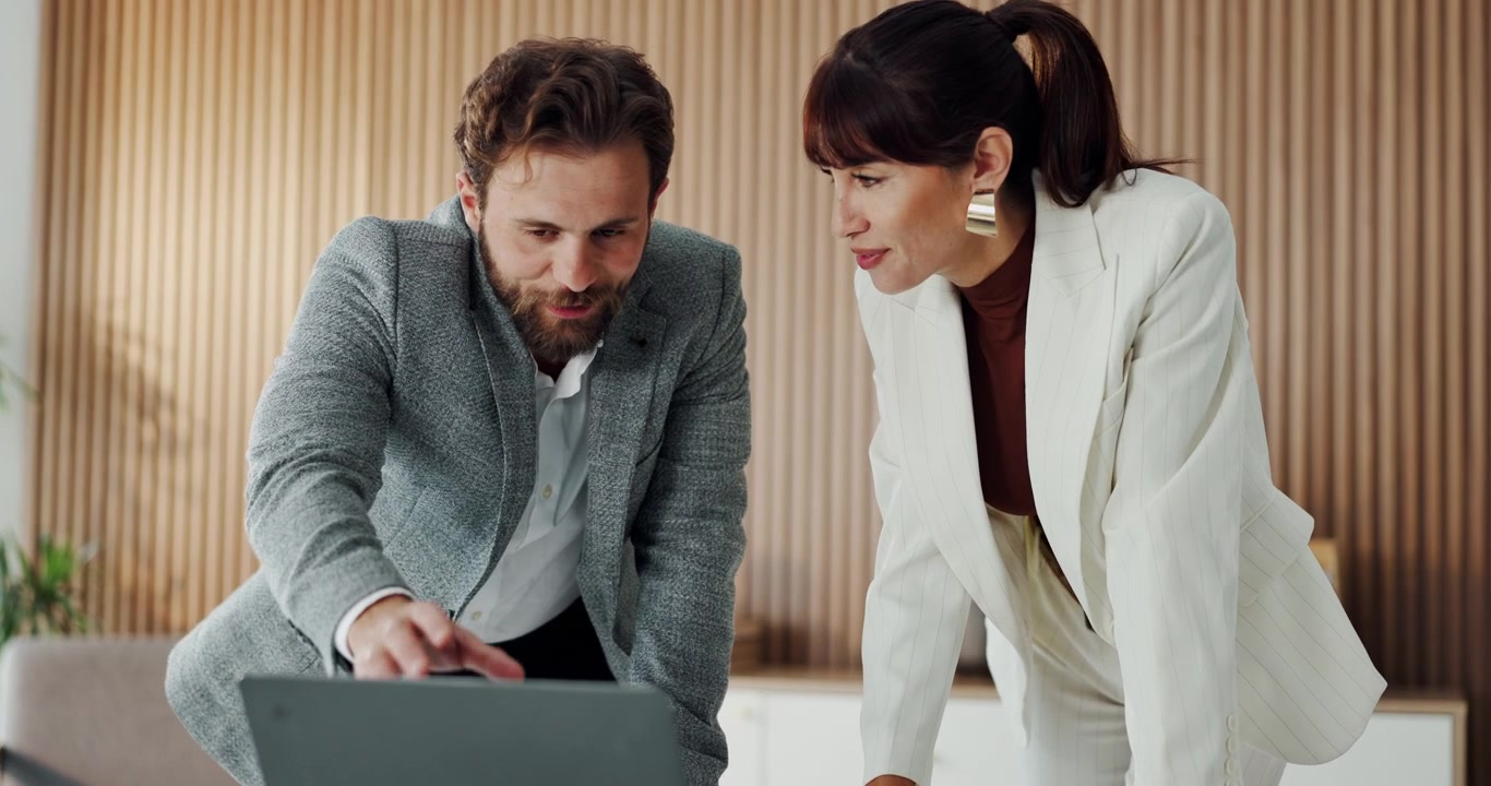 Colleghi professionisti che discutono di un progetto su un laptop in un ufficio moderno