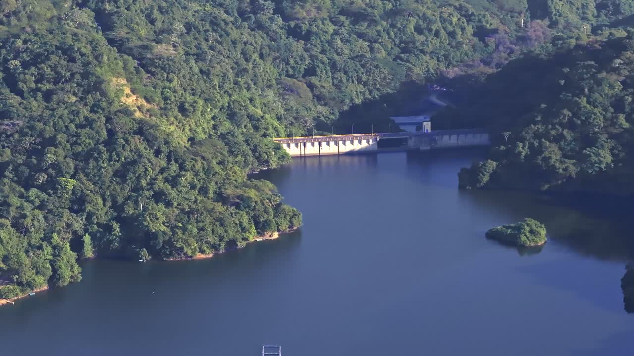 Aerial view of Rincon dam in samana surrounded by green mountains in Dominican Republic. Wide shot. Green mountains and blue river scene.