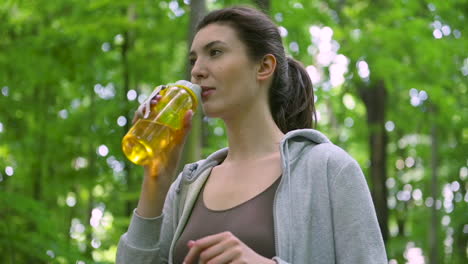 chica corredora bebiendo agua en el bosque después de correr