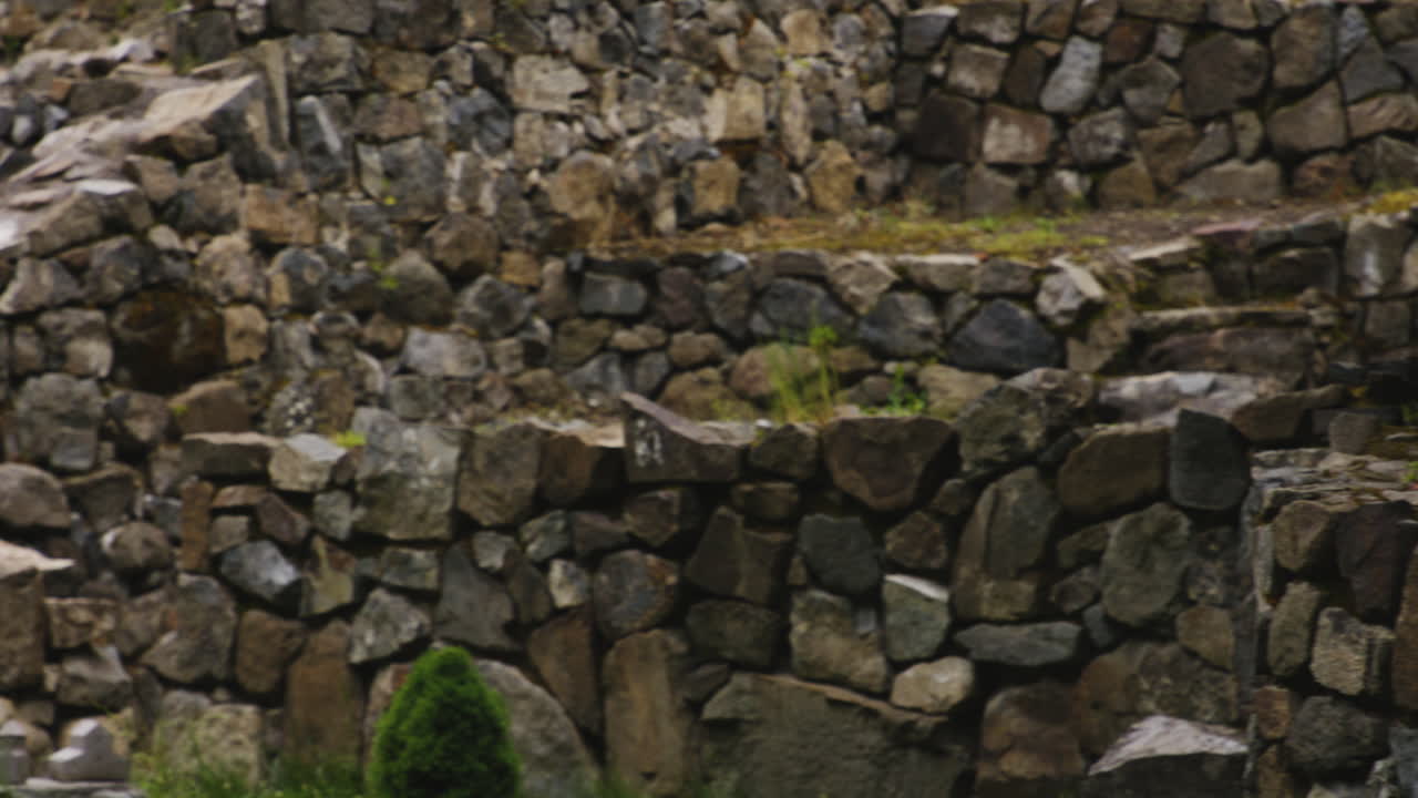 Croce in pietra ornata nel monastero di Mtsvane, con mura di pietra in rovina tutt'intorno.