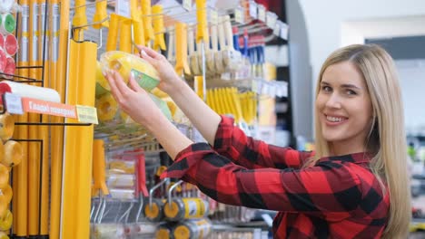 a woman is shopping for tools in a hardware store a customer a woman is shopping for tools in a retail building she gestures towards a shelf with shelving publications smiles and grabs a drink