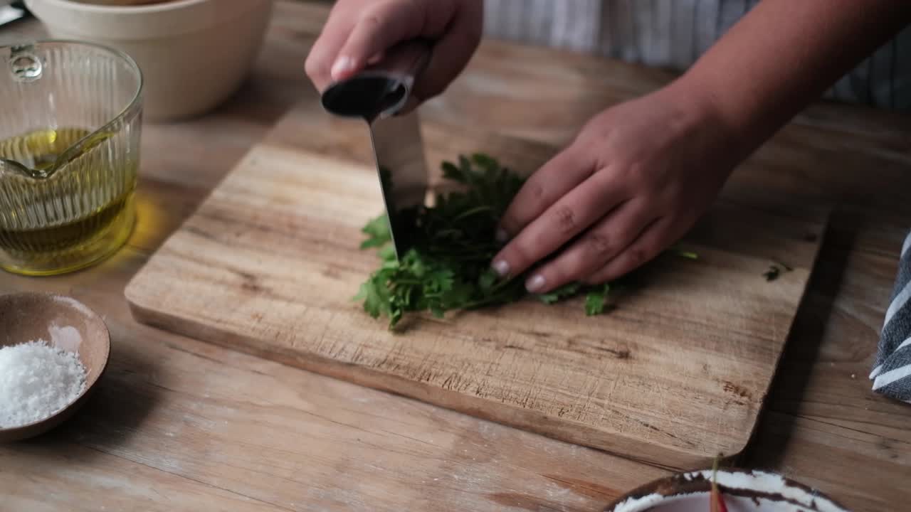 Chef cutting parsley on a wooden block