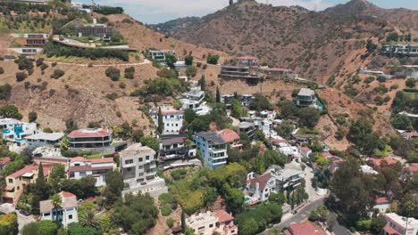 Aerial wide descending shot of upscale Hollywood Hills homes in Los Angeles, California. 4K