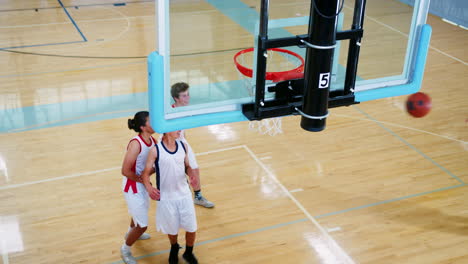 equipo masculino de baloncesto de la escuela secundaria anotando canasta en la cancha y celebrando