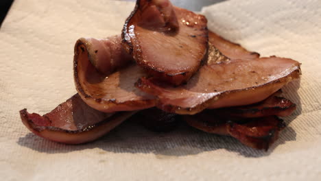 placing freshly cooked homemade bacon slices in paper towel to absorb excess oil