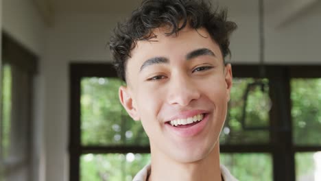 Portrait-of-happy-biracial-male-teenage-boy-at-home,-slow-motion