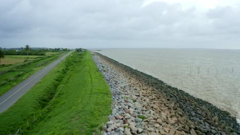 Aerial:-Sea-dyke-view-along-the-road,-fast-flyover,-North-Atlantic-Ocean-and-Nickerie-Suriname