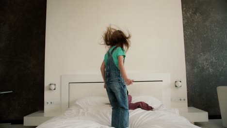 dos hermanas niñas se están divirtiendo saltando en la cama del dormitorio de sus padres