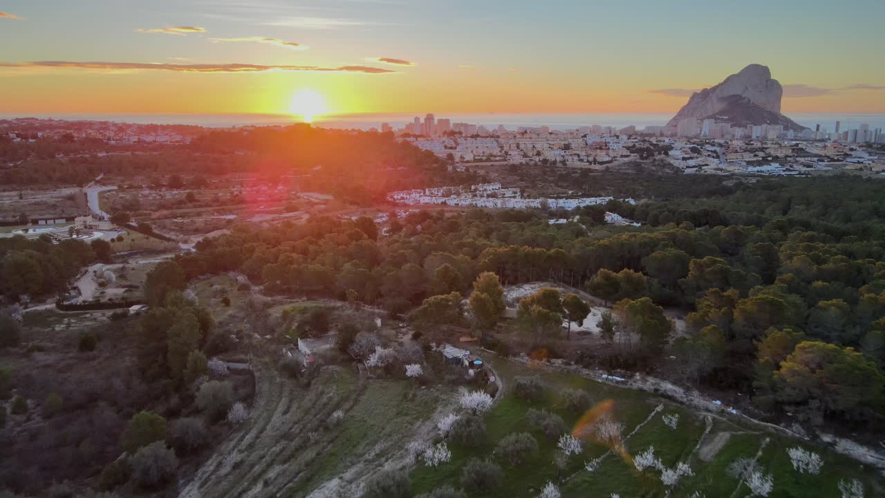 tomas panorámicas de drones del impresionante amanecer naranja sobre el campo valenciano, moviéndose hacia la ciudad de calpe, españa, y el parque natural con el emblemático peñón de ifach