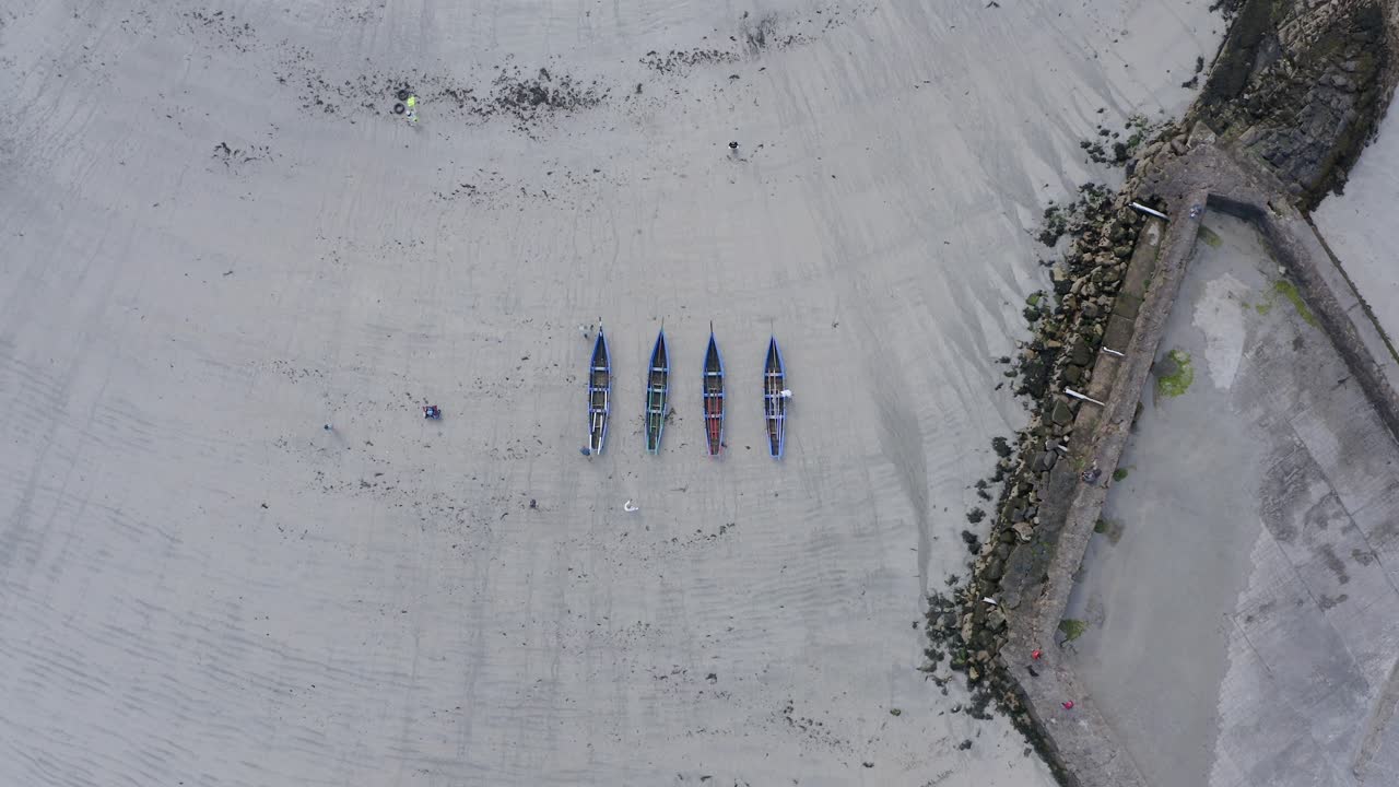 High bird's eye view descends on currach boats on sandy beach at galway ireland
