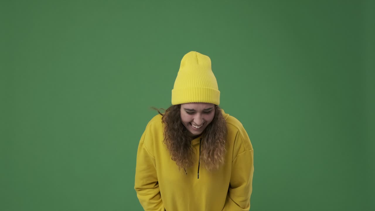 Frau lacht vor grünem Hintergrund.