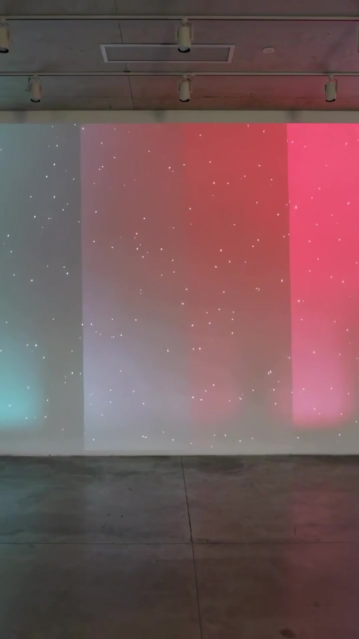 Vertical video: Projector starting hue animation shifting bands across gallery wall into warm red