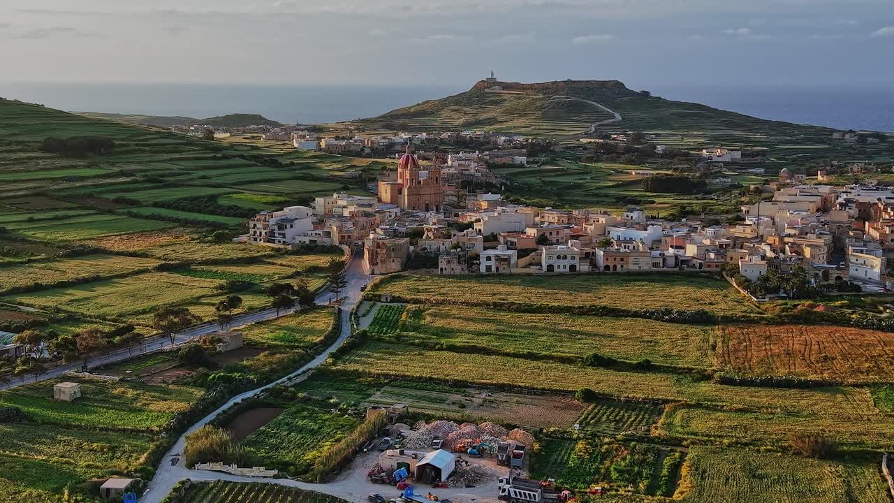 Vista sulla Malta rurale con città, campi e colline sotto un cielo sereno