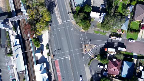 Paisaje-Drone-Aéreo-De-La-Carretera-Principal-Conjunto-De-Semáforos-Automóviles-Conduciendo-En-Los-Suburbios-De-Una-Pequeña-Ciudad-Junto-A-La-Estación-De-Tren-Ourimbah-Australia-Transporte-Viajes