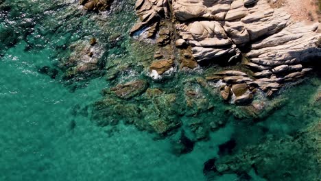 Forward-moving-Aerial-drone-clip-over-a-rock-formation-in-an-exotic-beach-in-Vourvourou,-Chalkidiki,-Greece