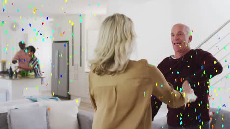 colorful confetti falling against caucasian senior couple dancing together at home