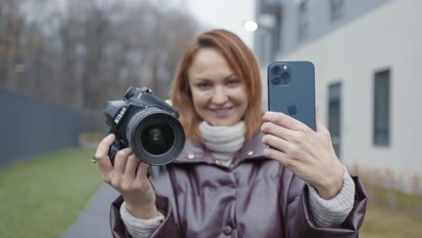 mujer comparando una cámara dslr con un teléfono inteligente